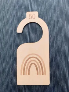 Wooden baby closet divider detail showing engraved number 50 and rainbow pattern on hook.