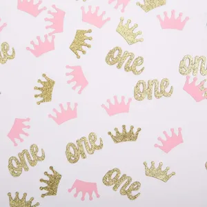 Close-up detail van gouden glitter one en roze kroon confetti stukjes voor tafeldecoratie.