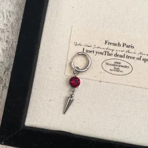 Detail view of gothic punk hoop earring featuring sparkling red rhinestone and metal spike pendant.