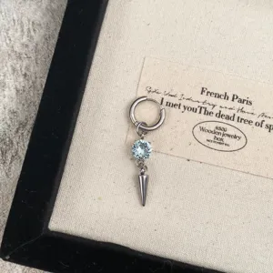 Detailed closeup of a stylish metal hoop earring with blue crystal and sharp cone pendant.
