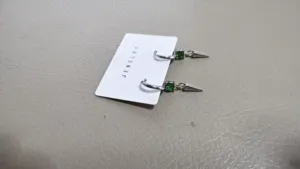 Green rhinestone spike pendant hoop earrings detail shot, chic and edgy style jewelry piece.