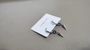 Spike charm hoop earrings with purple rhinestone, edgy statement jewelry detail.