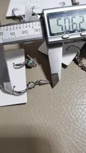 Close-up detail shot of sparkling rhinestone cone pendant earrings with precise caliper measurement.