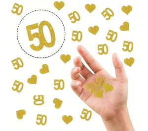 Close-up detail of gold glitter number 50 and heart confetti pieces held in hand for celebration.