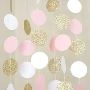 Primo piano di ghirlanda di cerchi di carta sospesi in rosa, bianco e glitter oro per feste.