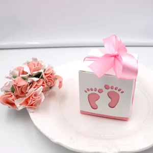 Pink baby shower favor box with cute hollow footprints and ribbon bow for party.