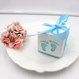 Detailed view of a white baby foot cutout candy gift box with blue ribbon for celebration.