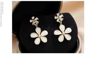 Élégantes boucles d'oreilles marguerite avec cristaux étincelants et pétales blancs opalescents.