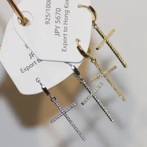 Close-up of pave rhinestone cross earrings detail with sparkling crystals and metal hoop clasp.