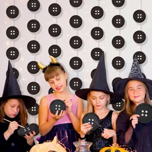 Detalle de decoración de fiesta de botones de Halloween con guirnaldas y platos temáticos.