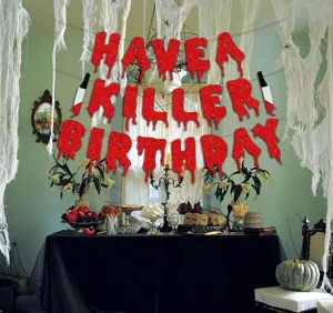 Detailed view of Halloween party banner with blood knife and glitter letters for creepy decor.