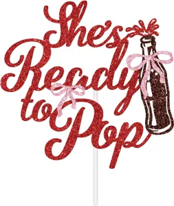 Detailed view of sparkly red She's Ready to Pop cake topper for baby shower party decor.