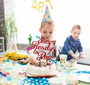 Red glitter cake topper scene detail for baby birthday party celebration and sweet dessert decor.