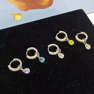 Detailed view of colorful teardrop crystal hoop earrings set on black velvet display.