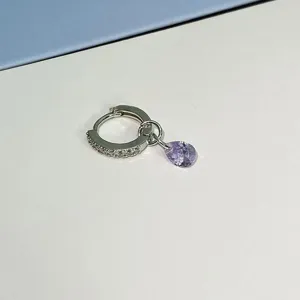 Close-up detail of silver hoop earring featuring micro pavé zircon and a dangling purple teardrop crystal.