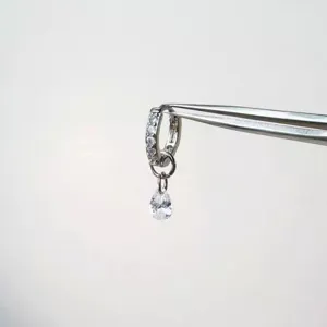 Close-up of silver paved zirconia hoop earring with dangling teardrop crystal pendant.
