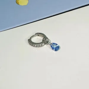 Close-up detail of silver hoop earring with pavé crystals and blue teardrop pendant.