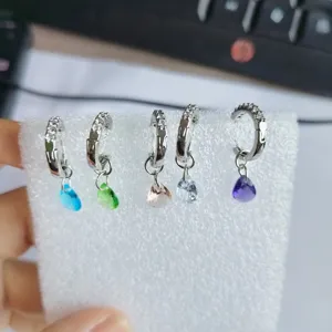 Detailed close-up shot of colorful teardrop crystal hoop earrings adorned with full sparkling diamonds.