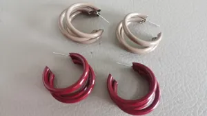 Detailaufnahme von mehrschichtigen C-förmigen Metall-Ohrringen mit feinem Lackfinish.
