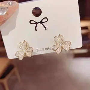 Detailed view of sparkly rhinestone clover earrings on white card, elegant jewelry detail.