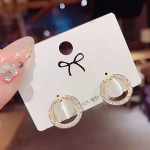 Detail shot of elegant geometric round cat eye earrings with sparkling rhinestone accents.