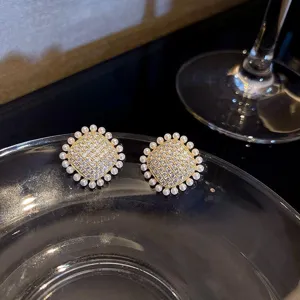Primo piano dettagliato di lussuosi orecchini quadrati in strass con elegante bordo di perle.