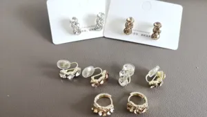 Detailansicht von Strassohrringen und Ohrclips mit funkelnden Kristallen in Goldton.