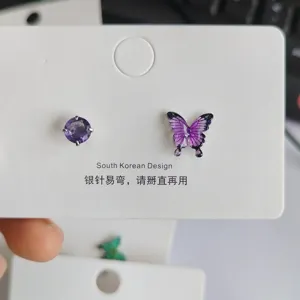 Detailansicht asymmetrischer lila Schmetterling Zirkon Ohrstecker auf weißer Displaykarte.