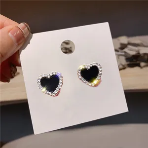 Close-up detail van stijlvolle zwarte hart oorbellen met sprankelende strass rand.