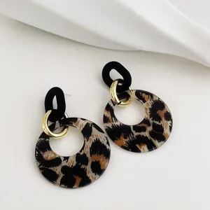Close-up detail of trendy fashion acrylic leopard print geometric circle earrings with gold metal rings.