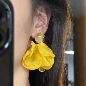 Close-up detail shot of yellow chiffon flower earrings, showing delicate fabric texture.