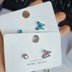 Nahaufnahme bunter Schmetterlings-Ohrstecker mit feinen Kristall-Details, eleganter Stil.