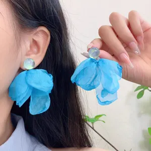 Close-up detail shot of elegant blue fabric flower earrings for women, resort style.