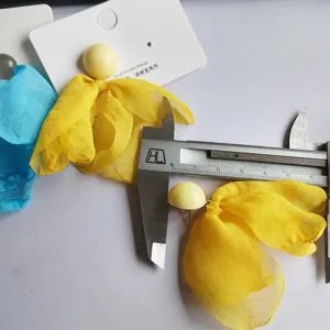 Detailed view of yellow fabric petal earrings with a card and caliper size measurement.
