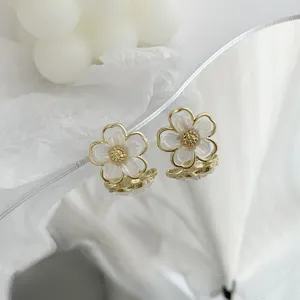 Close-up detail of retro gold-rimmed white flower stud earrings with delicate floral design.