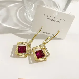 Elegante geometrische Ohrringe mit leuchtenden lila Kristallen und funkelnden Zirkonia.