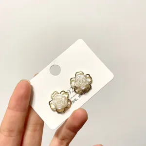 Close-up of elegant flower pearl stud earrings with 925 silver needle, delicate floral design.