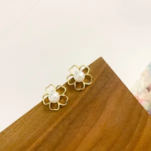 Close-up detail view of elegant gold flower pearl stud earrings, showcasing delicate openwork design.