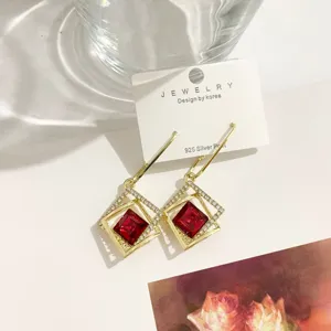 Nahaufnahme von luxuriösen geometrischen quadratischen Ohrringen mit funkelnden Zirkonia und Gold.