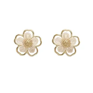 Close-up detail view of elegant gold-rimmed floral stud earrings with pearlescent petals.