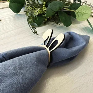 Wooden bunny ear napkin ring with blue cloth napkin for table setting and Easter party decor.