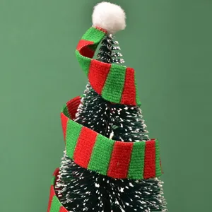 Primer plano de un mini árbol de Navidad decorado con una bufanda de punto a rayas.