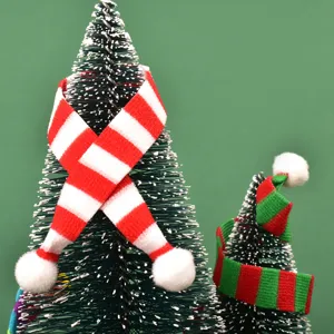 Detalle de mini árbol de Navidad, pequeña bufanda tejida a rayas, accesorio festivo.