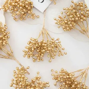 Close-up details of gold artificial berry branches for Christmas wreaths and DIY craft projects.
