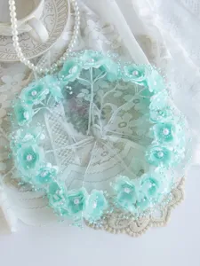 Nahaufnahme von mintgrünen künstlichen Blumen-Haaraccessoires mit Perlen, handgefertigtes Design.