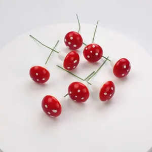 Nahaufnahme von roten Mini Schaumstoff Pilzen mit weissen Punkten und gruenen Drahtstielen.