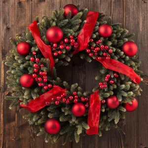 Detailed close-up view of artificial Christmas wreath with pine needles and red berries.