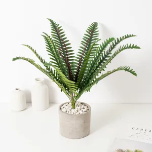 Pianta di felce artificiale nordica in vaso di cemento grigio con ciottoli bianchi.