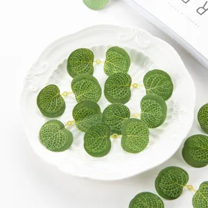 Dettaglio di foglie di eucalipto artificiali con venature chiare e fori per lavoretti fai da te.