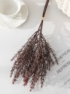 Vue détaillée de la branche de pin artificielle, feuillage marron réaliste pour la décoration florale.